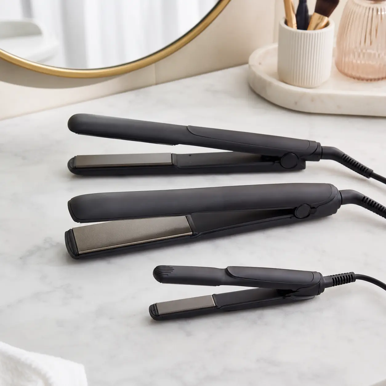 Standard wide plate and compact travel hair straighteners compared on a dressing table
